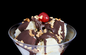 A chocolate sundae with chopped nuts and a cherry on top.